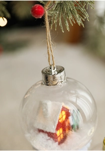 Detalle de bola de Navidad LED transparente con casa en miniatura y nieve artificial