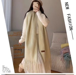 Close-up of beige plush scarf texture with fringes and a premium brand woven label