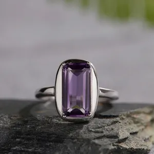 Macro shot of emerald-cut natural amethyst ring on grey stone, 925 silver band