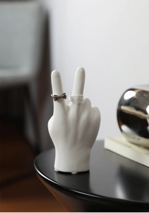 Detail of silver bow and chain rings displayed on white ceramic hand sculpture decor