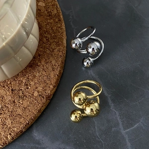 Close-up of gold and silver triple bead rings on a textured marble background