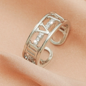 Detailed shot of silver ring with Roman numerals and pavé cubic zirconia on pink silk
