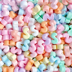Macro shot of colorful resin S-shaped letter charms for DIY crafts and accessories