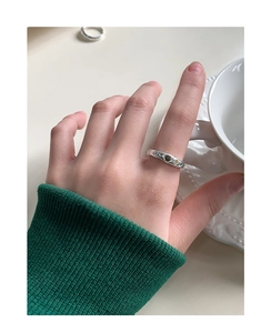 Close-up of S925 sterling silver ring with colorful zircons on finger next to white cup