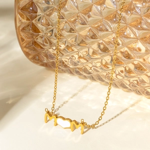 Détail du collier MOM plaqué or 18 carats avec pendentif coeur près d'un vase en verre