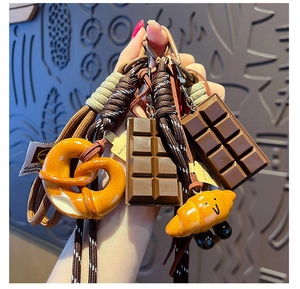Close-up of creative pretzel and croissant charms on a woven lanyard keychain with metal clasp