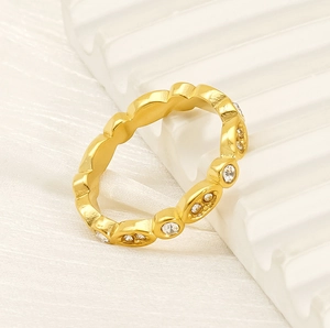 Detail shot of a slim gold twisted ring with inlaid white zircon stones on wave pattern
