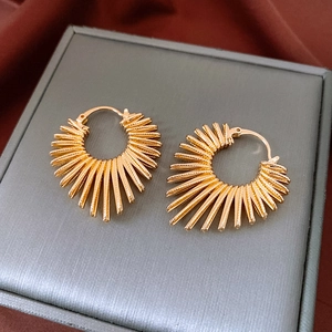 Detailed view of gold sunburst textured earrings on velvet fabric with professional finish