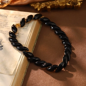 Close-up of vintage enamel necklace with black almond beads and gold metallic accents