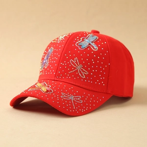 Detailed view of red baseball cap featuring sparkling rhinestone dragonfly embroidery
