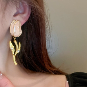 Gros plan sur boucle d'oreille tulipe rose et feuilles dorées sur le mannequin