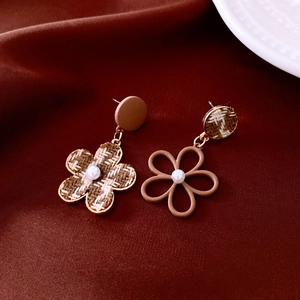 Dettaglio di orecchini a fiore in tweed asimmetrici con perle su velluto rosso