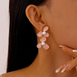 Detailed view of model wearing pink floral pearl earrings with gold plating finish
