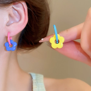 Close-up of colorful glass flower charm earrings with vibrant blue and yellow petals