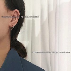 Close-up of minimalist silver daisy hoop earring worn on model against a soft background