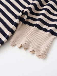 Detail of navy stripe knit top featuring scalloped hem and decorative hollow-out design