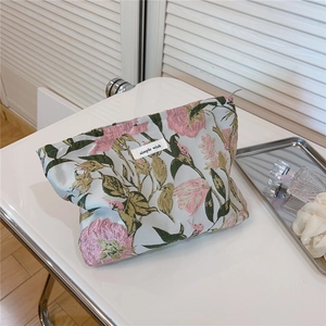 Detailed macro view of a floral jacquard makeup bag with a minimalist woven label