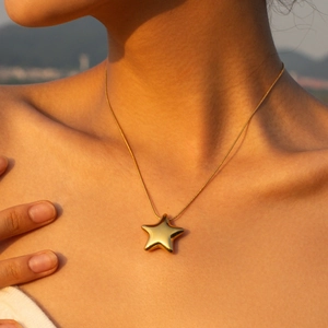 Classic 18K gold plated stainless steel necklace with star pendant worn in sunset light