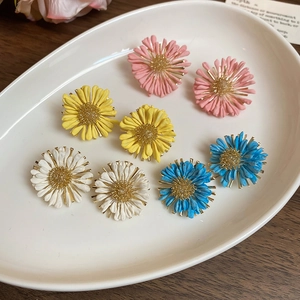 Close-up of four pairs of colorful daisy stud earrings on a white plate