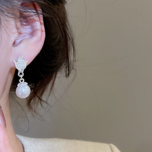 Close-up of silver bow and pearl earring on model showcasing elegant vintage style