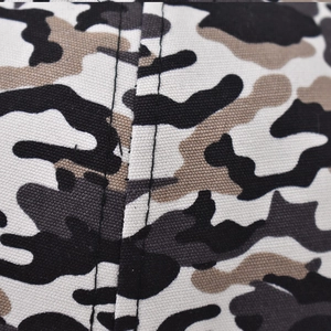 Macro detail of camouflage fabric with black double stitching on a twill cotton cap