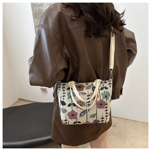 Fashionable floral tapestry crossbody bag with beige strap shown on a model's back
