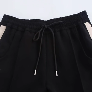 Detail of black sports shorts featuring elastic waistband, drawstrings and white side stripes