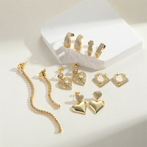 Close-up of gold earrings with cubic zirconia hearts and star details on stone props