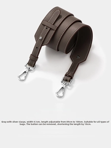 Detail of adjustable gray leather bag strap with silver metal hooks and pebble texture