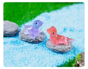Macro detail of miniature purple and pink resin lizard figurines on moss and stones
