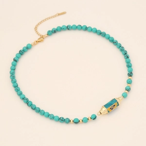 Detail of turquoise beaded necklace featuring a gold Yoga pendant and lobster clasp