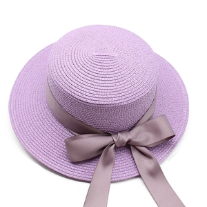 Chapeau de paille plat mauve avec ruban gris-violet et grand nœud sur fond blanc