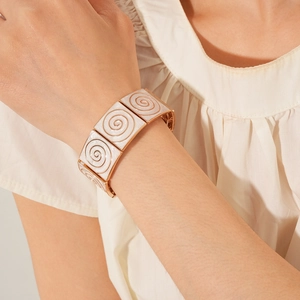 Rose gold elastic bracelet with cream enamel and swirl texture on model wrist