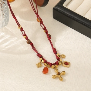 Detailed shot of ethnic red woven necklace with gold cross pendant and carnelian beads