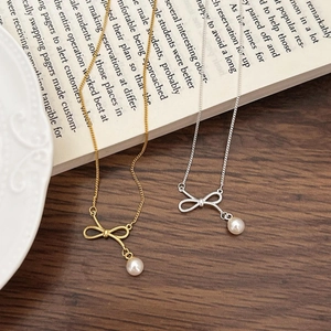 Detail of silver and gold bow pearl necklaces on an open book with wooden background