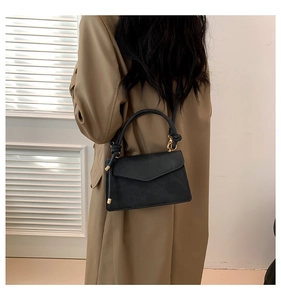 Détail du sac à main noir mat avec poignée nouée et fermoir pivotant doré