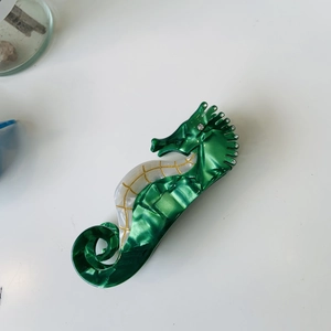 Detail of green marble acetate seahorse hair claw with sparkling rhinestone accents