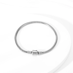 Detailed view of silver snake chain bracelet with barrel clasp on white textured background