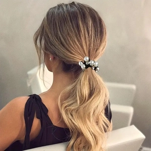 Detailansicht eines eleganten Perlen-Haargummis mit Strass in einem klassischen Pferdeschwanz