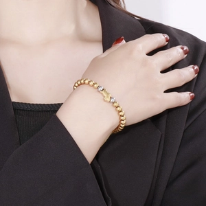 Close-up of gold and silver beaded elastic bracelet with a central Pixiu charm on wrist