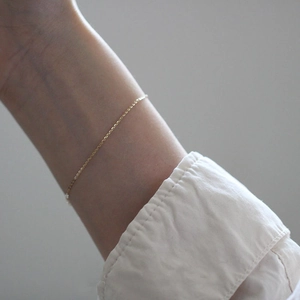 Minimalist 14k gold plated 925 sterling silver thin chain bracelet on model's wrist