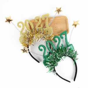 Serre-têtes festifs Nouvel An 2027 avec étoiles et glands pailletés or et vert sur fond blanc