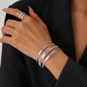 Detail of silver layered bracelet set and textured ring on wrist with black suit