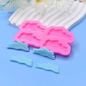 Pink silicone mold featuring four rabbit cavities with finished blue bunny crafts