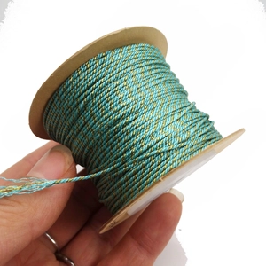 Detailed view of 1mm teal and gold metallic twisted thread roll for DIY jewelry making
