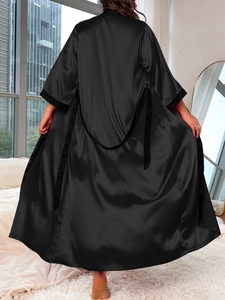 Detail of elegant black satin lounge robe showing smooth texture and loose-fitting design