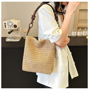 Rainbow woven straw bucket bag with wooden bead strap detail worn by model outdoors