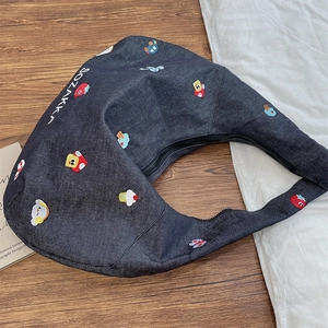 Detail of embroidered strawberry and cupcake patterns on blue denim shoulder bag