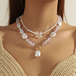 Close-up of a double-layered baroque pearl necklace with floral pendant on a model