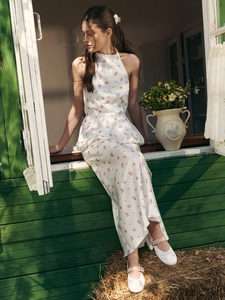 Close-up of white floral halter dress with ruffled waist detail and pink flower patterns